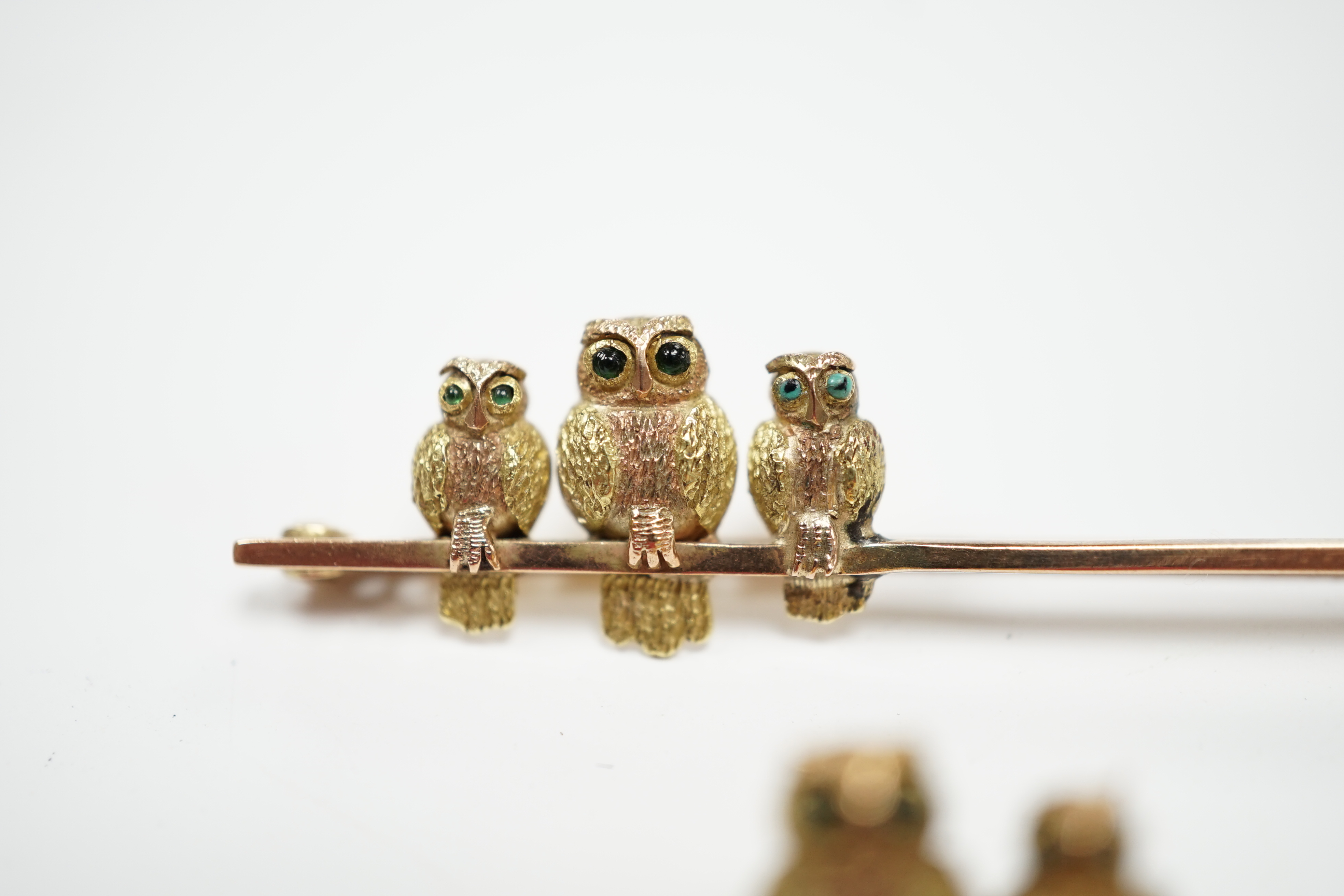 Two early 20th century 9ct owl bar brooches, with cabochon set eyes, largest 63mm, gross weight 6.9 grams.